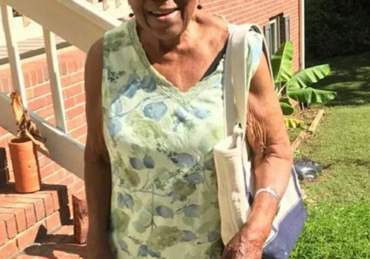 Grannie Annie in a floral dress standing on a staircase outdoors